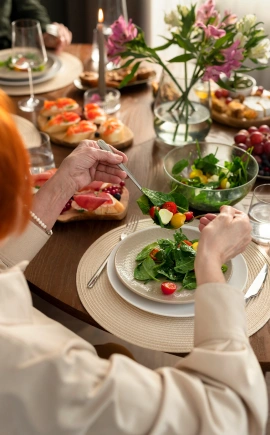 Woman at a table full of gourmet foods, serving herself salad